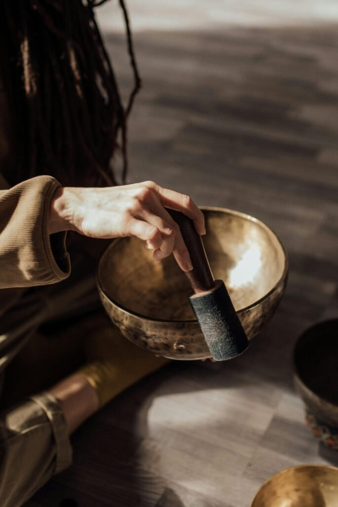 pexels-photo-6997988-6997988 Hand holding a mallet over a Tibetan singing bowl for meditation practice.